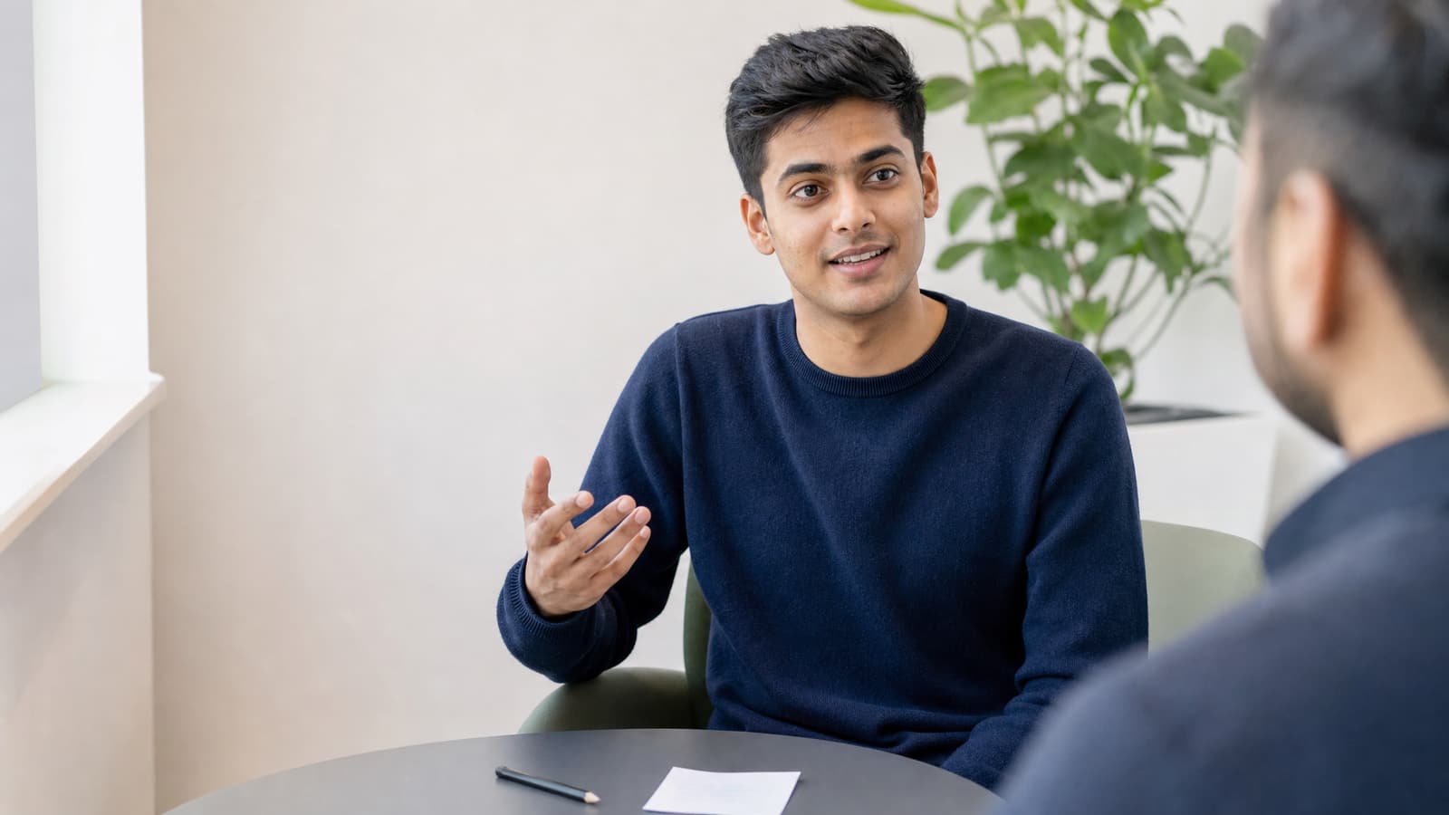 A student answering an IELTS Speaking Part 2 question with his task card on the table